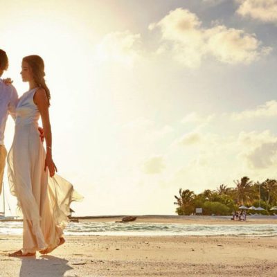 Paar in leichter Brautkleidung auf einer Sandbank auf den Malediven. Kurz bevor die Sonne untergeht