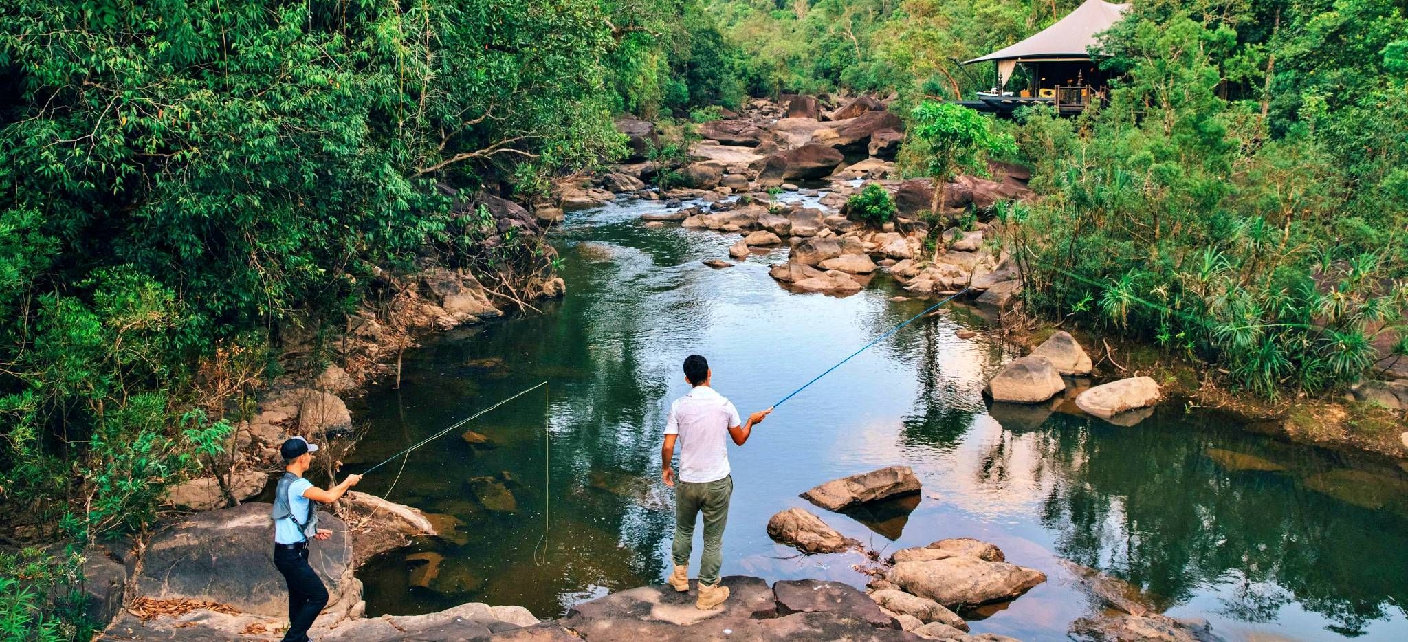 Zwei Männer fischen im Fluss neben einem Zimmer des Hotels Shinta Mani Wild, Kambodscha