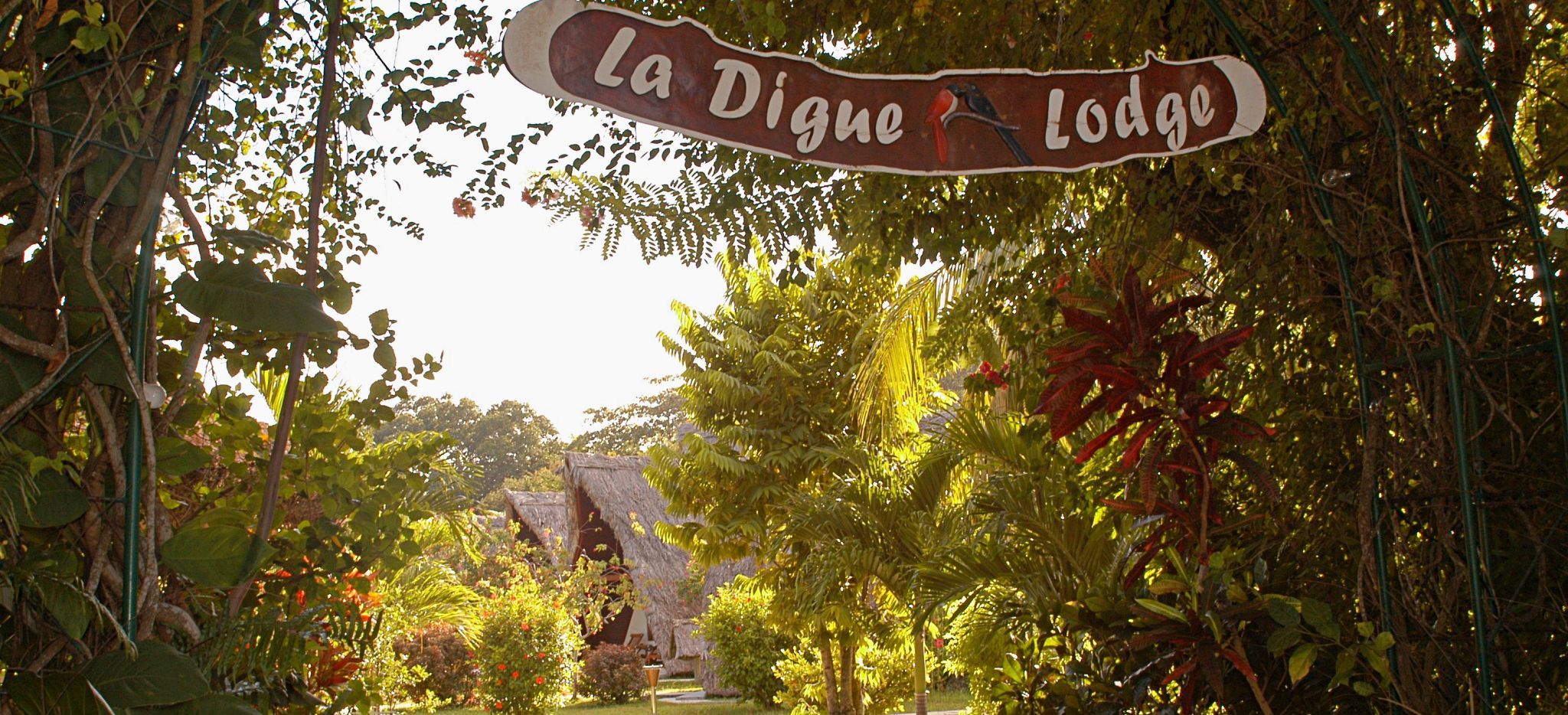 Eingangsbereich mit Schild "La Digue Lodge" im Grünen