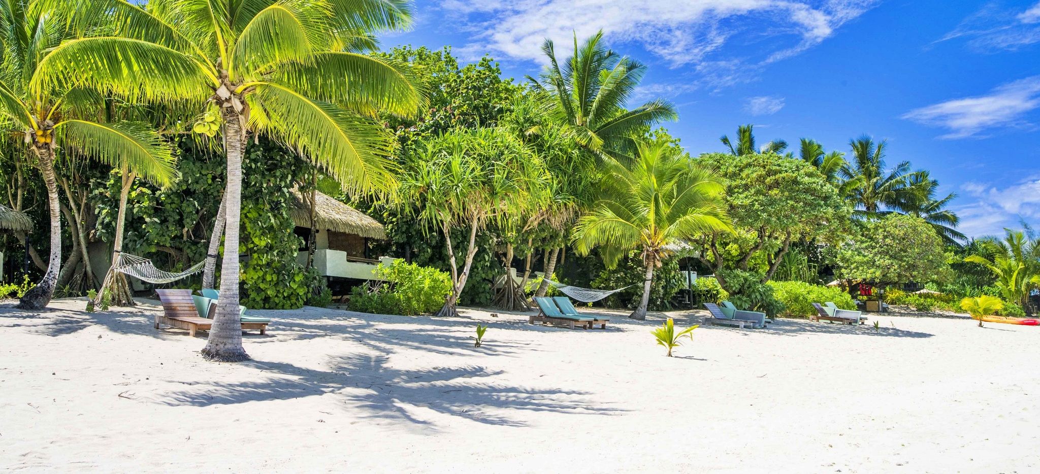 Strand vor dem Pacific Resort Aitutaki mit Liegen und Hängematten