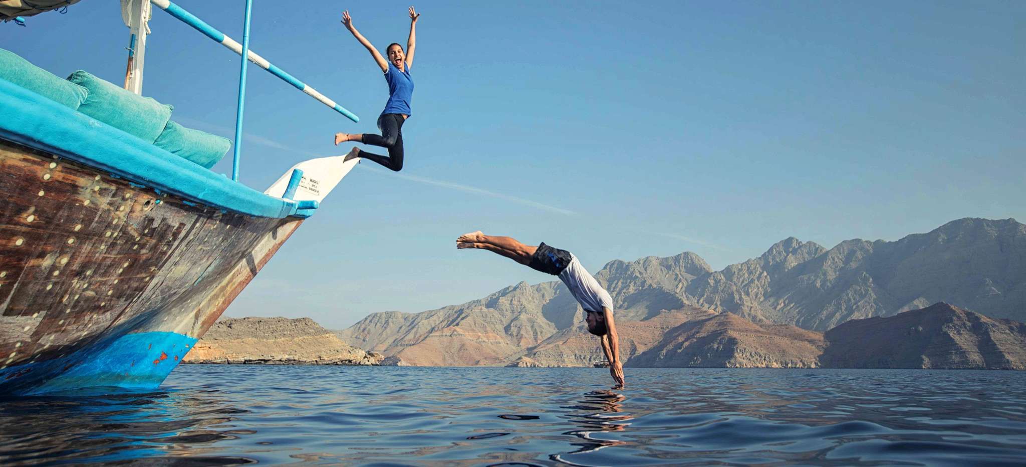 paar springt von einem Boot ins Meer, Nahe Musandam im Oman