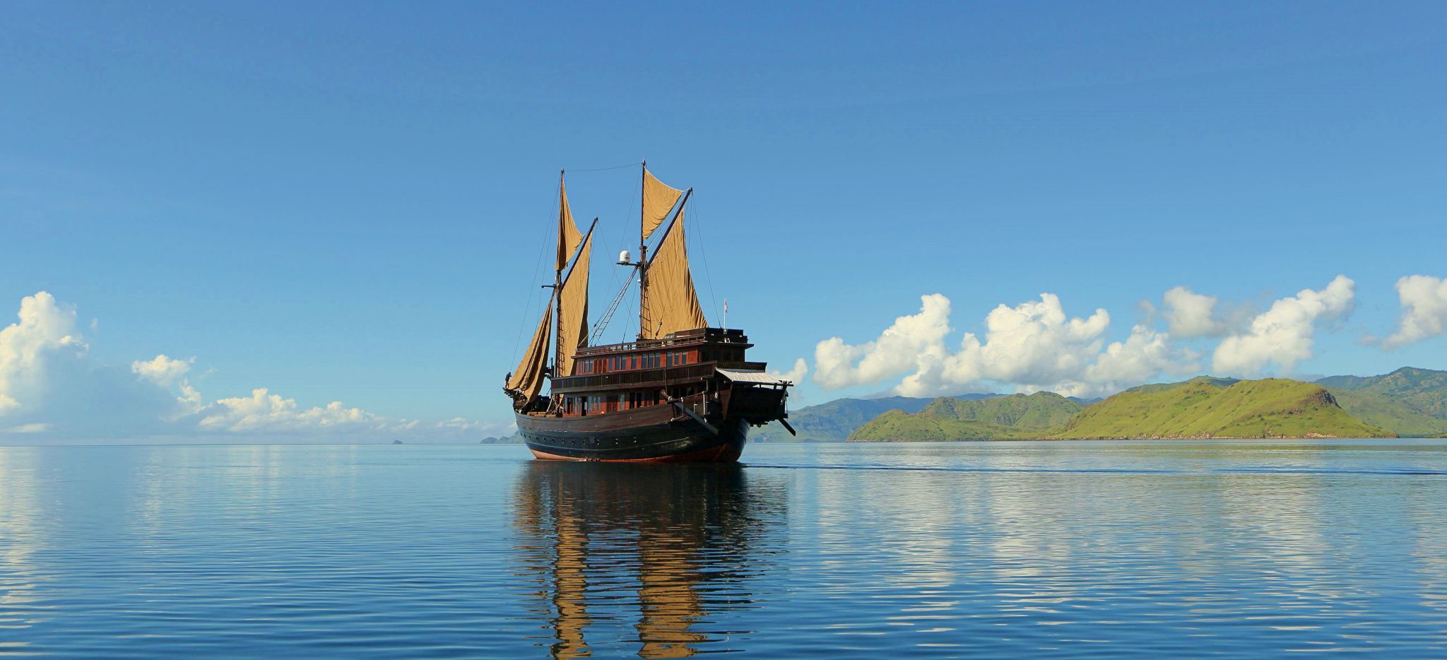 Die Yacht "Alila Purnama" auf dem Meer, mit Inseln im Hintergrund