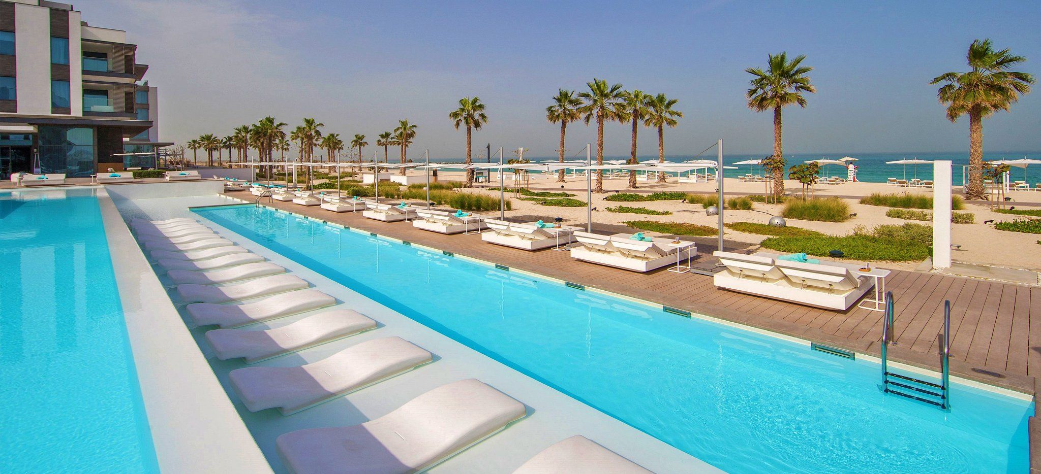 Ein sehr langer, Palmenumsäumter Pool im Hotel Nikki Beach Dubai