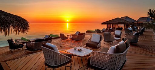Sonnenuntergang hinter einer Über-Wasser Terasse mit Kaffeetischen des Waldorf Astoria Maldives