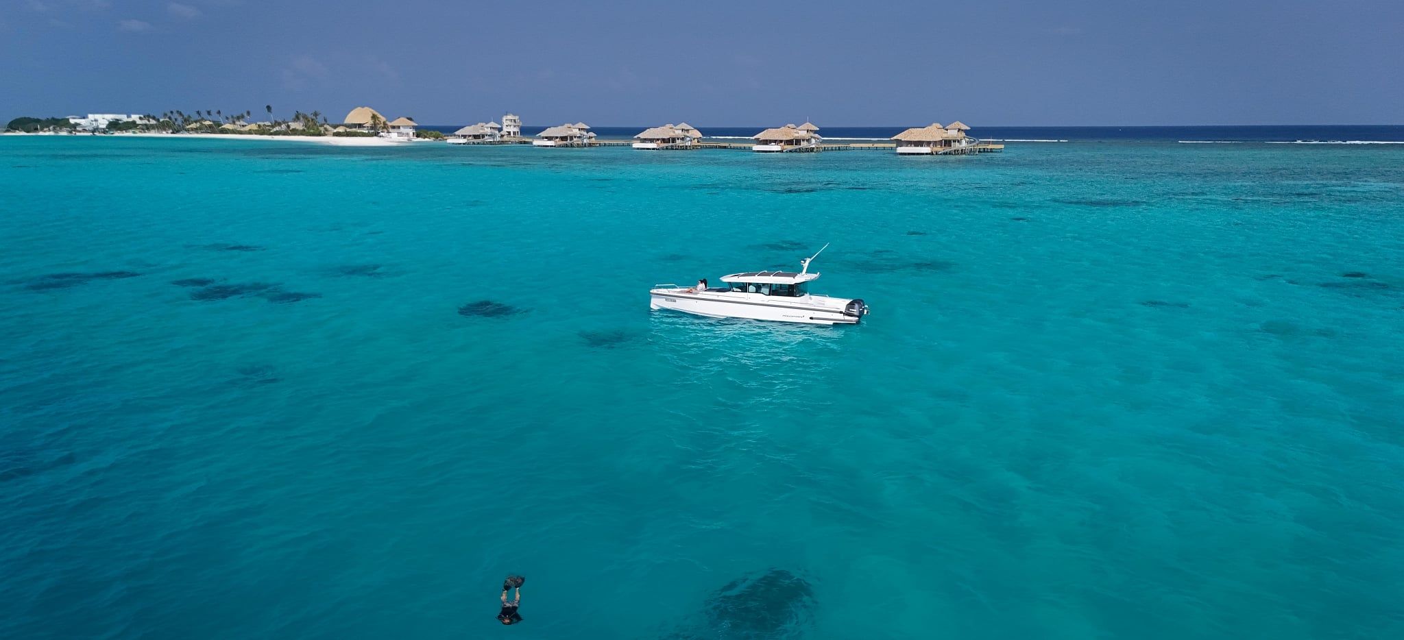 Ein Schnorchler im Meer der Malediven, mit der Hotelinsel Soneva Secret am Horizont