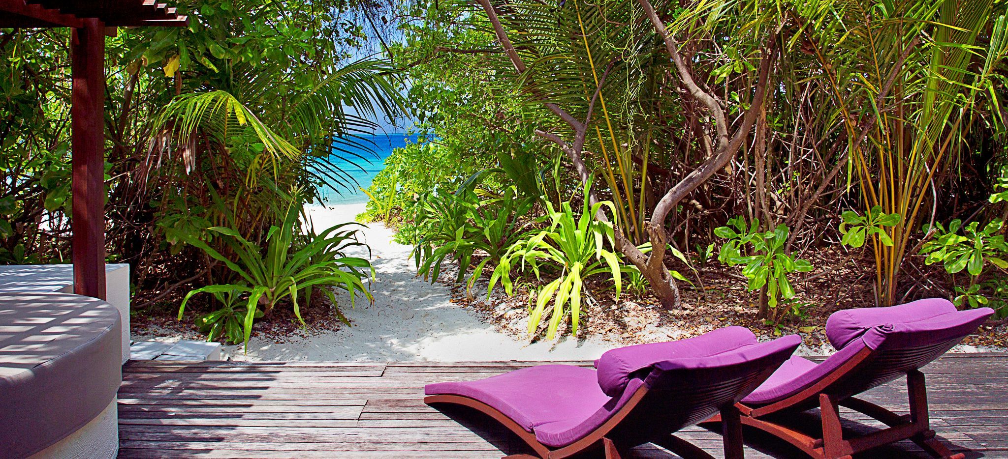 Blick auf das Meer zwischen Büschen von der Terrasse eines Hotelzimmers im Hotel Coco Palm Bofu Hithi auf den Malediven