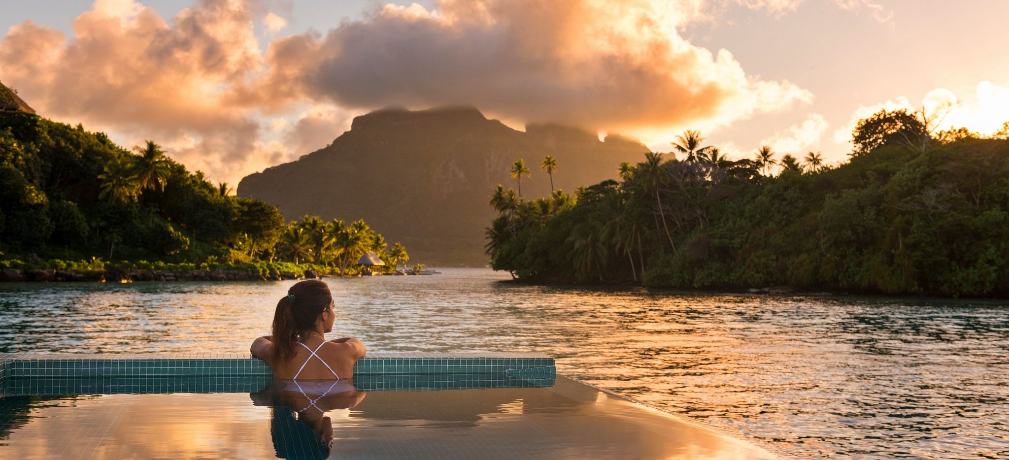 Eine Frau blickt aus dem Pool der Royal Villa im Hotel "Conrad Bora Bora Nui" auf die Insel Bora Bora