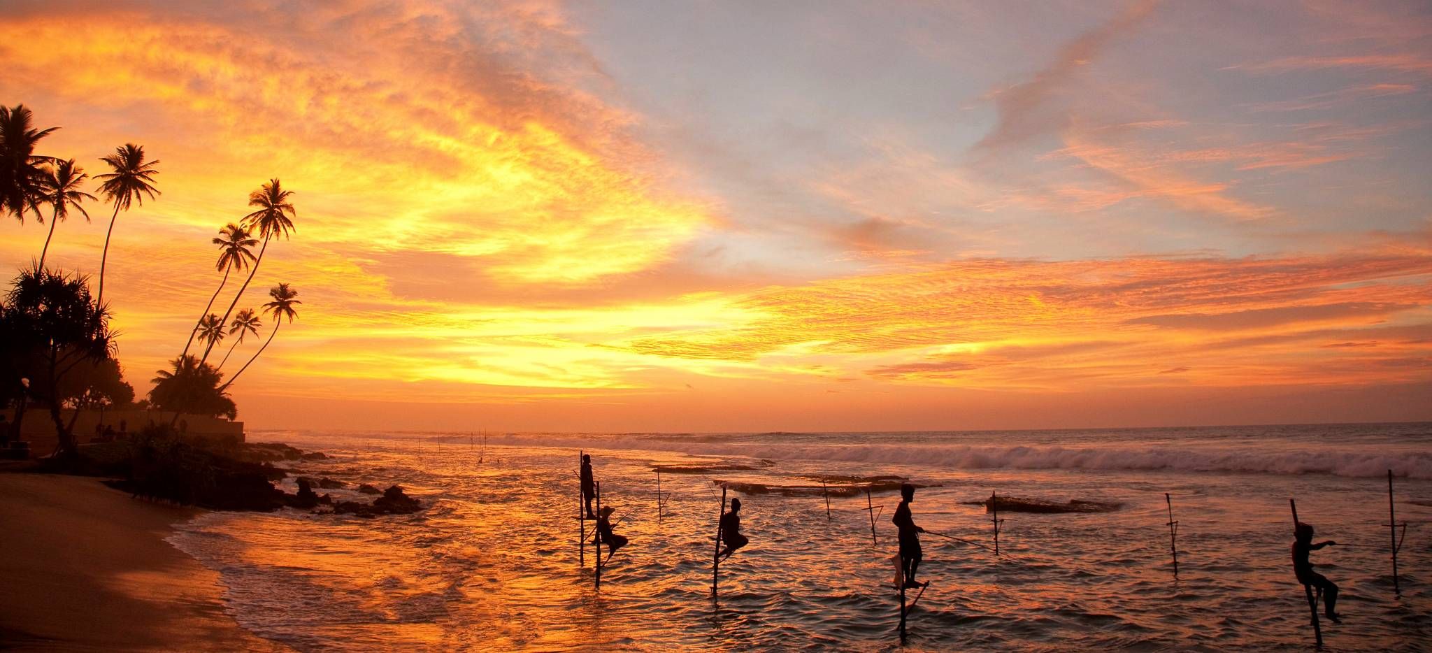 Manner fischen auf Stelzen im Wasser an einem Strand auf Sri Lanka, im Abendrot
