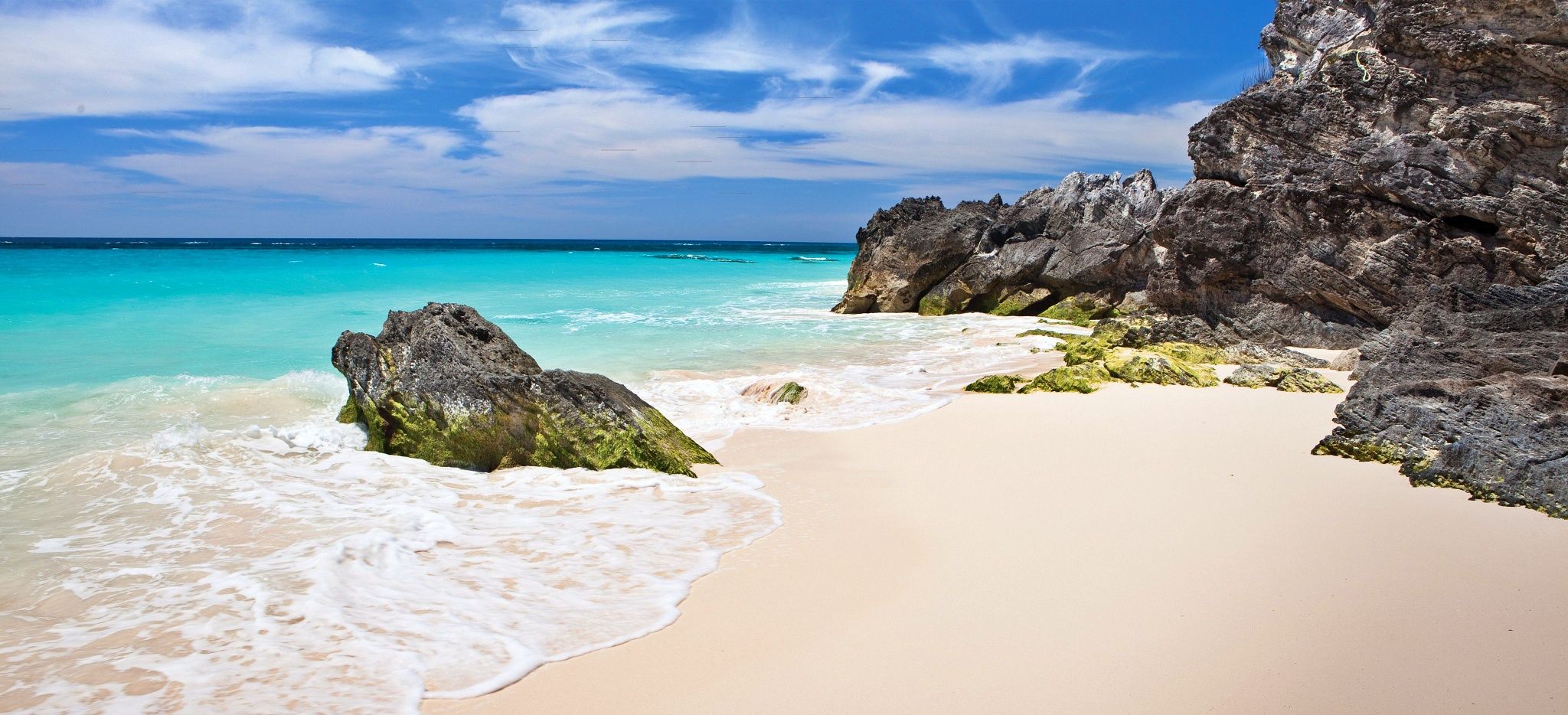 Ein weißer Sandstrand mit großen Felsen vor dem Hotel "Rosewood Tucker's Point" auf den Bermudas