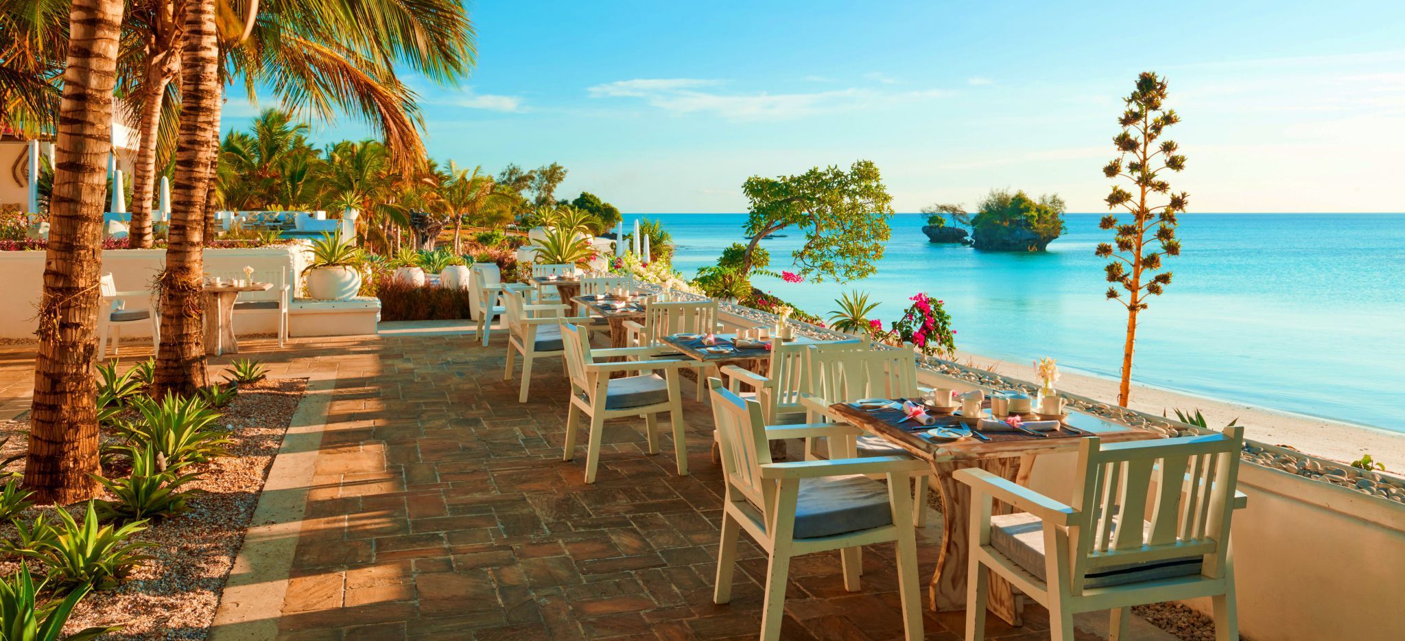 Ein paar Restauranttische mit Blick auf das Meer, im Hotel the Aiyana auf Pemba, Tansania