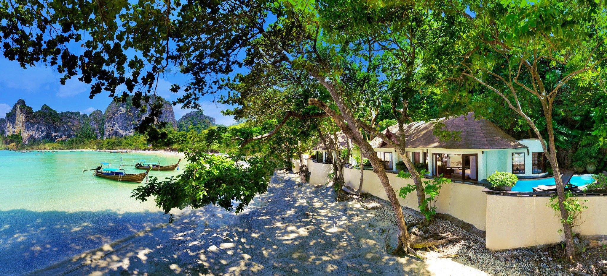 Eine Villa am Strand, der im Schatten großer, wilder Laubbäume liegt