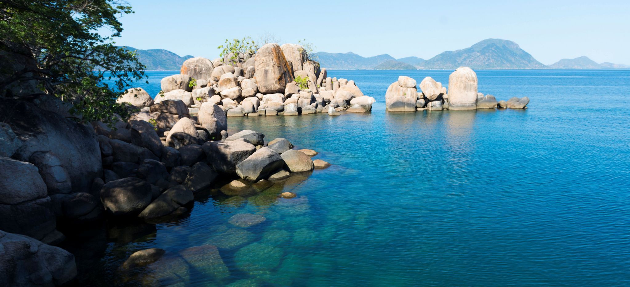 Blick auf den blauen Malawisee, die andere Küste in der Ferne, Felsen im Bild