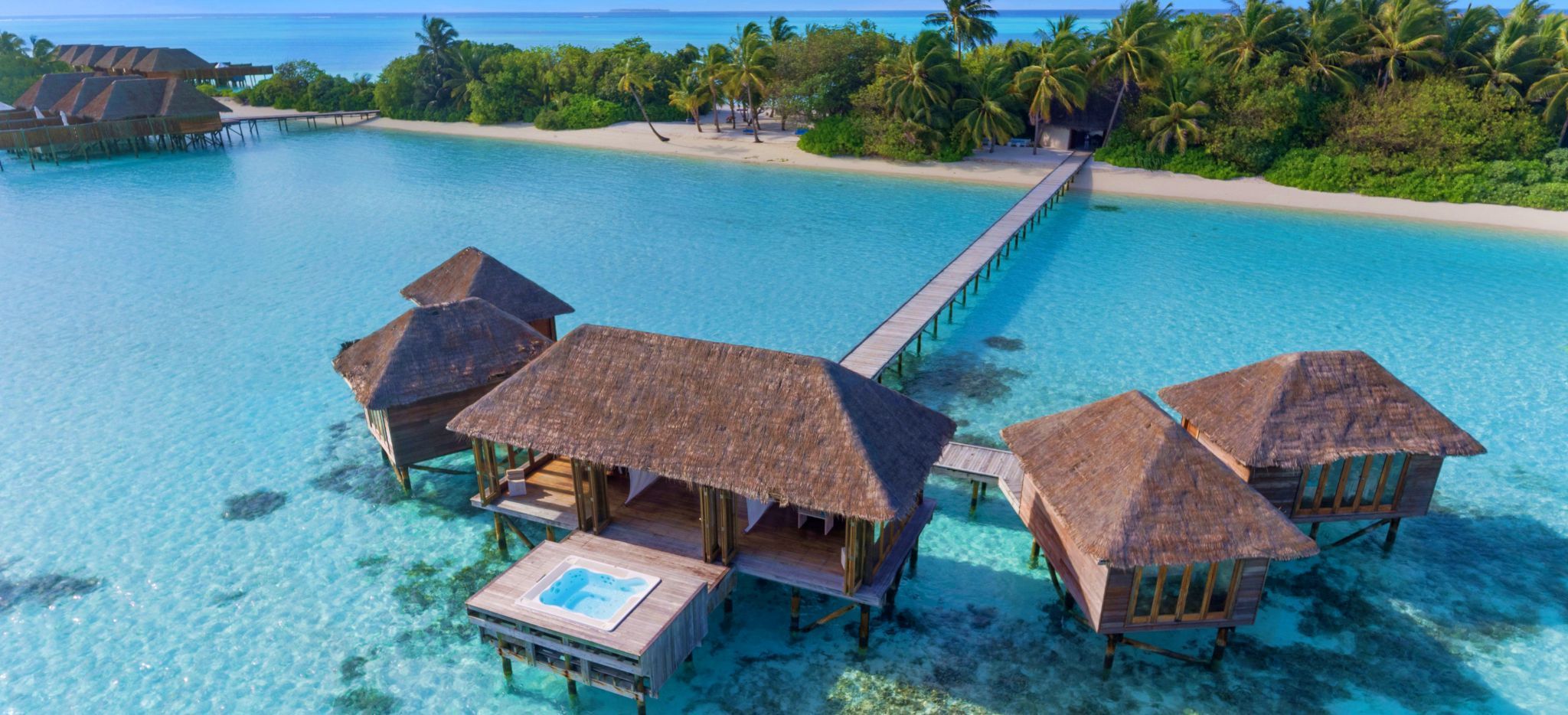 Eine Wasservilla, in der sich ein Wellness-Bereich befindet. Im Hintergrund die Hotelinsel Conrad Maldives