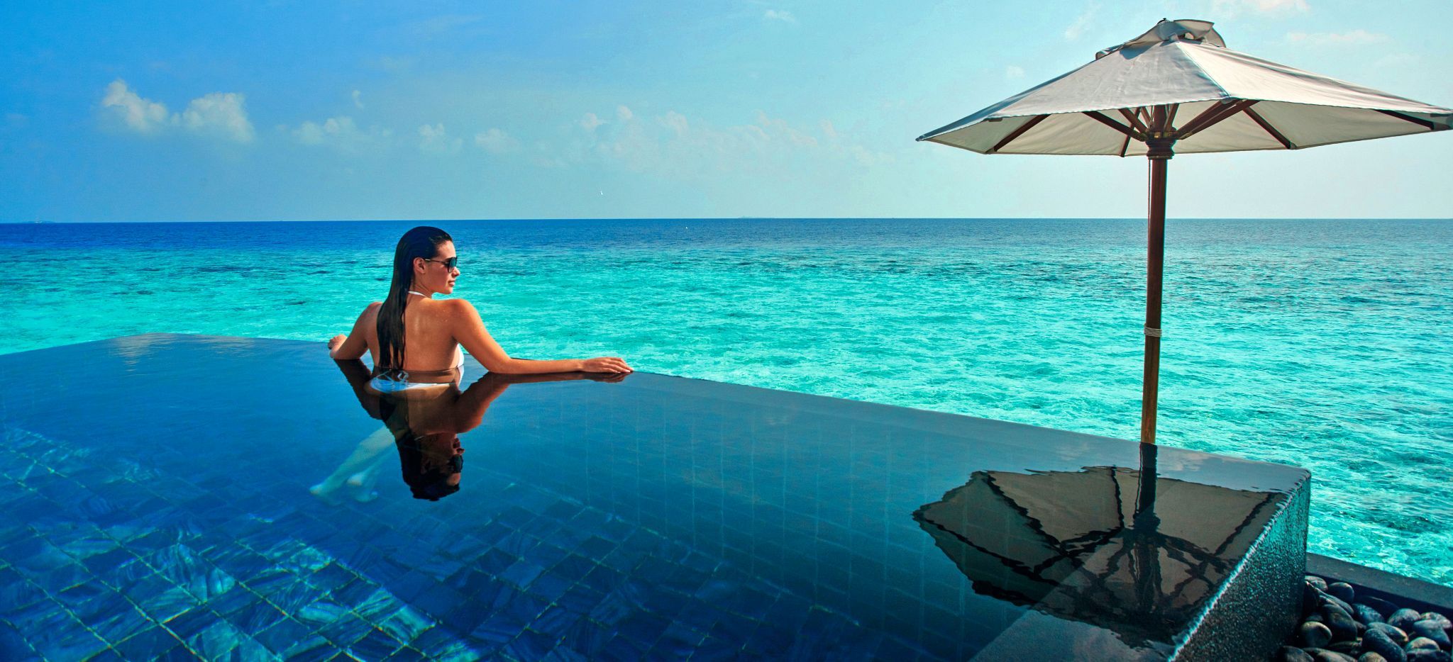 Eine Frau schwimmt in einem privaten Pool einer Wasservilla in der Lagune des Hotels Constance Halaveli