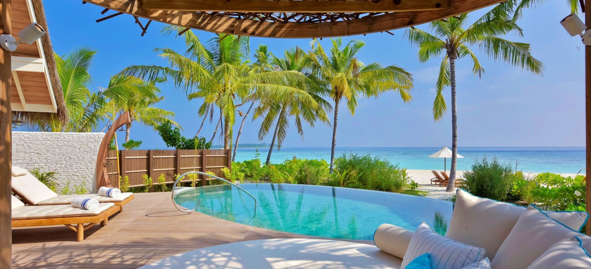 Meerblick von der Terrasse eines weitläufigen, freistehenden Hotelzimmers, über einen Pool und den Strand