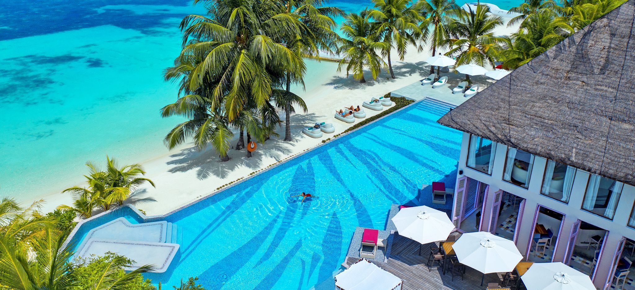 Ein großer Pool direkt am Strand vor einem Restaurant auf der Malediveninsel Madhoo