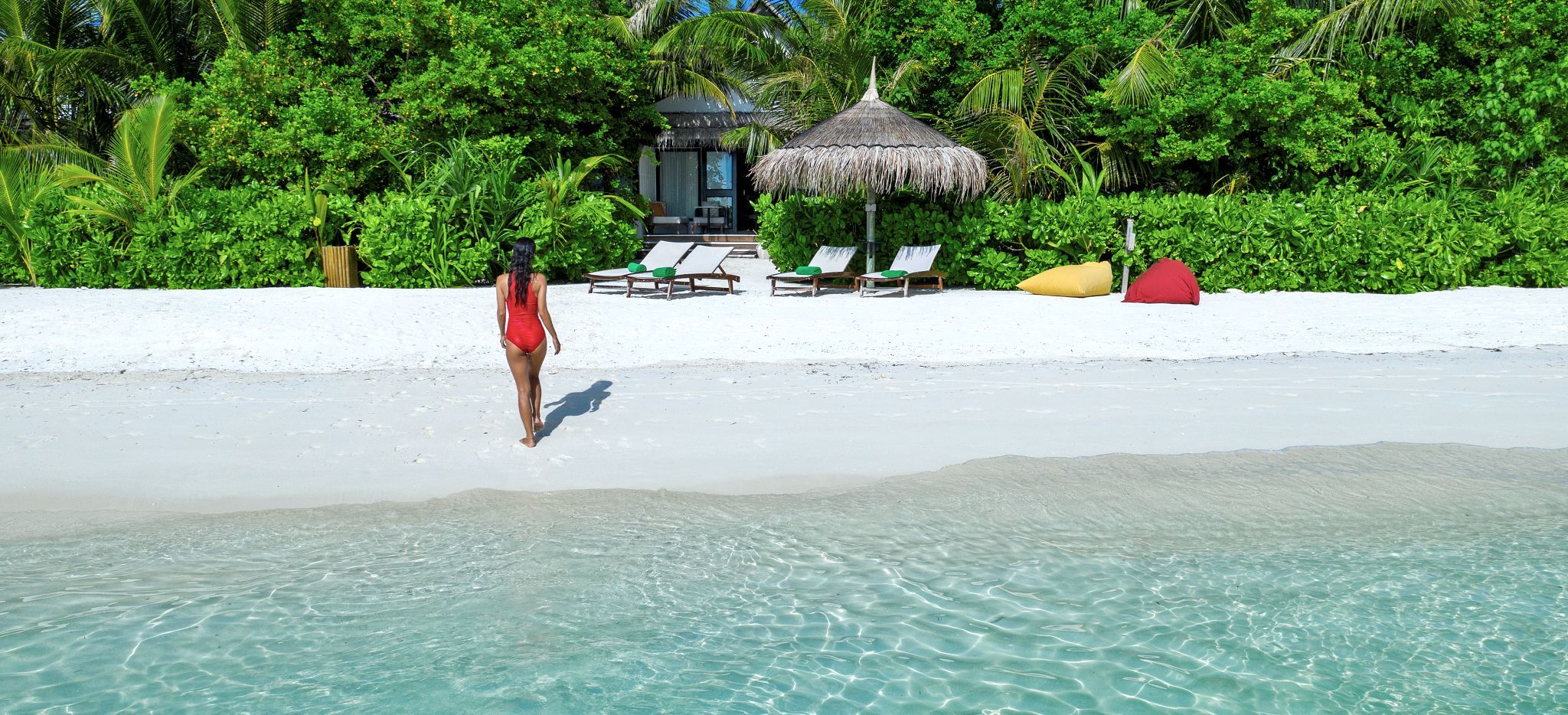 Eine Frand wandert am weißen Strand einer Malediveninsel. Das Hotelzimmer Earth Pool Pavillon im Hotel OZEN.