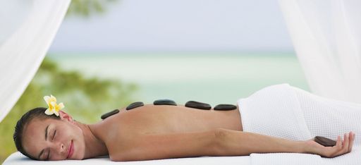 Eine Frau genießt eine Hot Stone Massage auf einer Liege am Strand