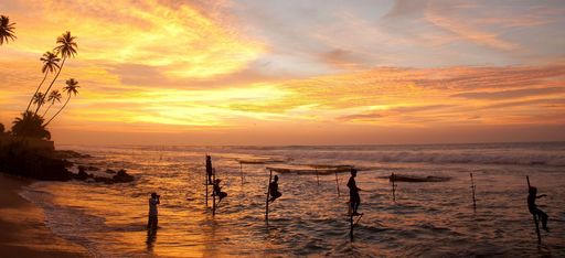 Fischer auf Stelzen am Strand im Abendrot, Sri Lanka