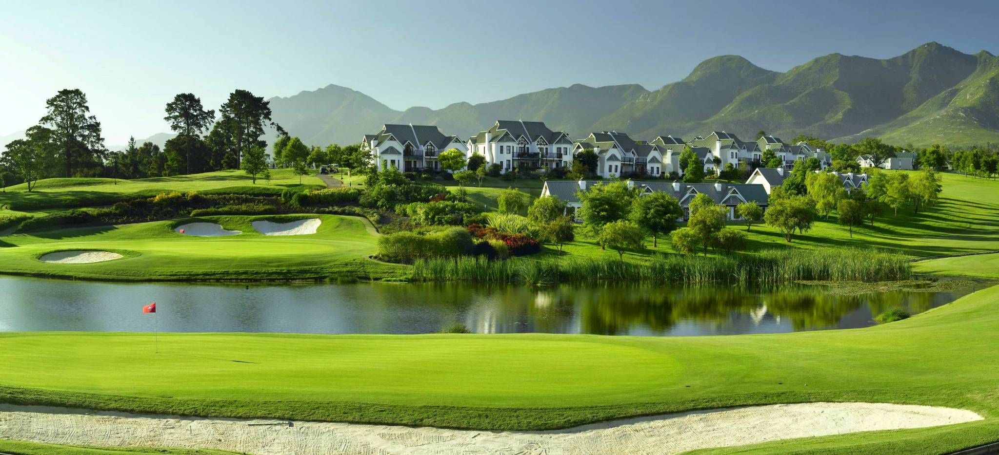 Golfplatz mit ausladenden Teichen vor einer Bergkulisse in Südafrika