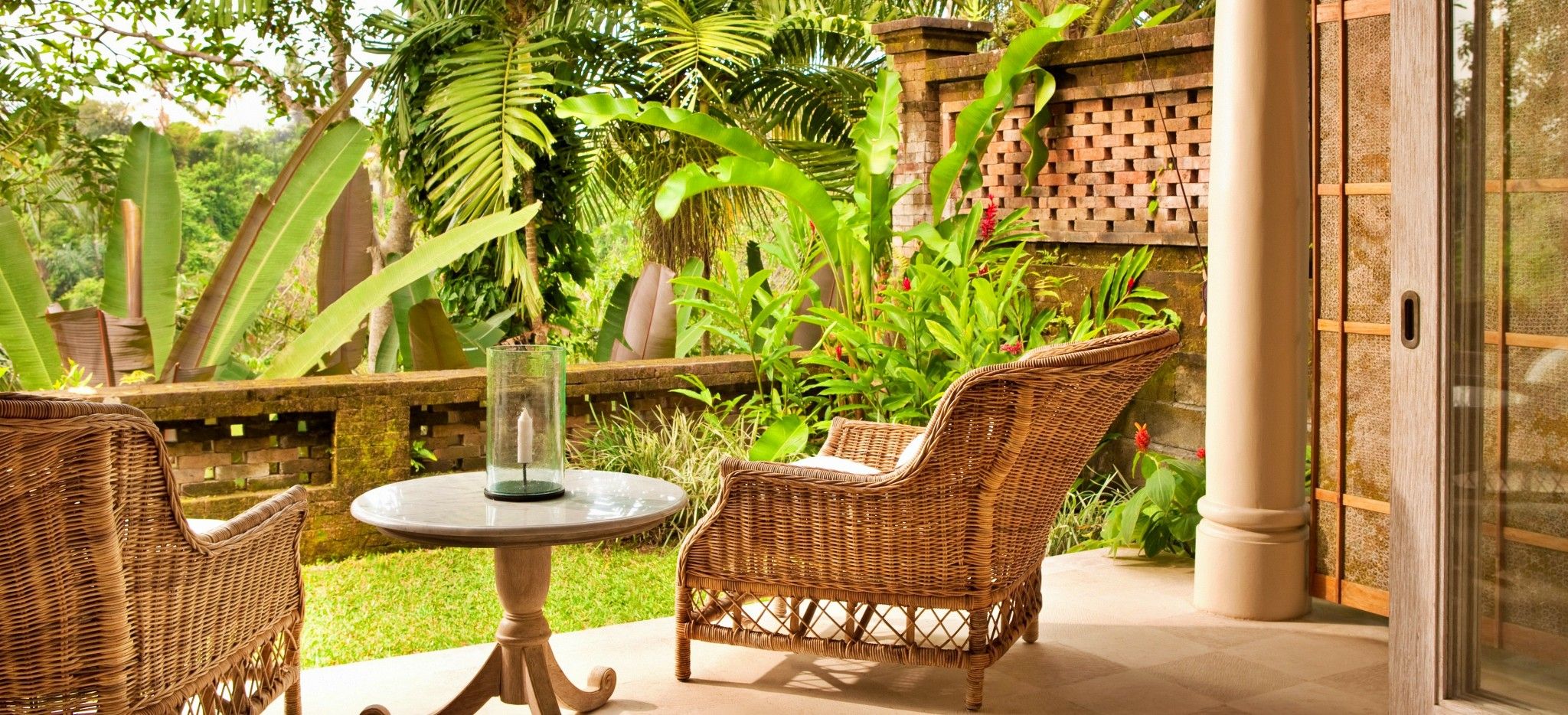 Eine Terrasse mit zwei Rattan-Sesseln mit Blick auf einen balinesischen Garten