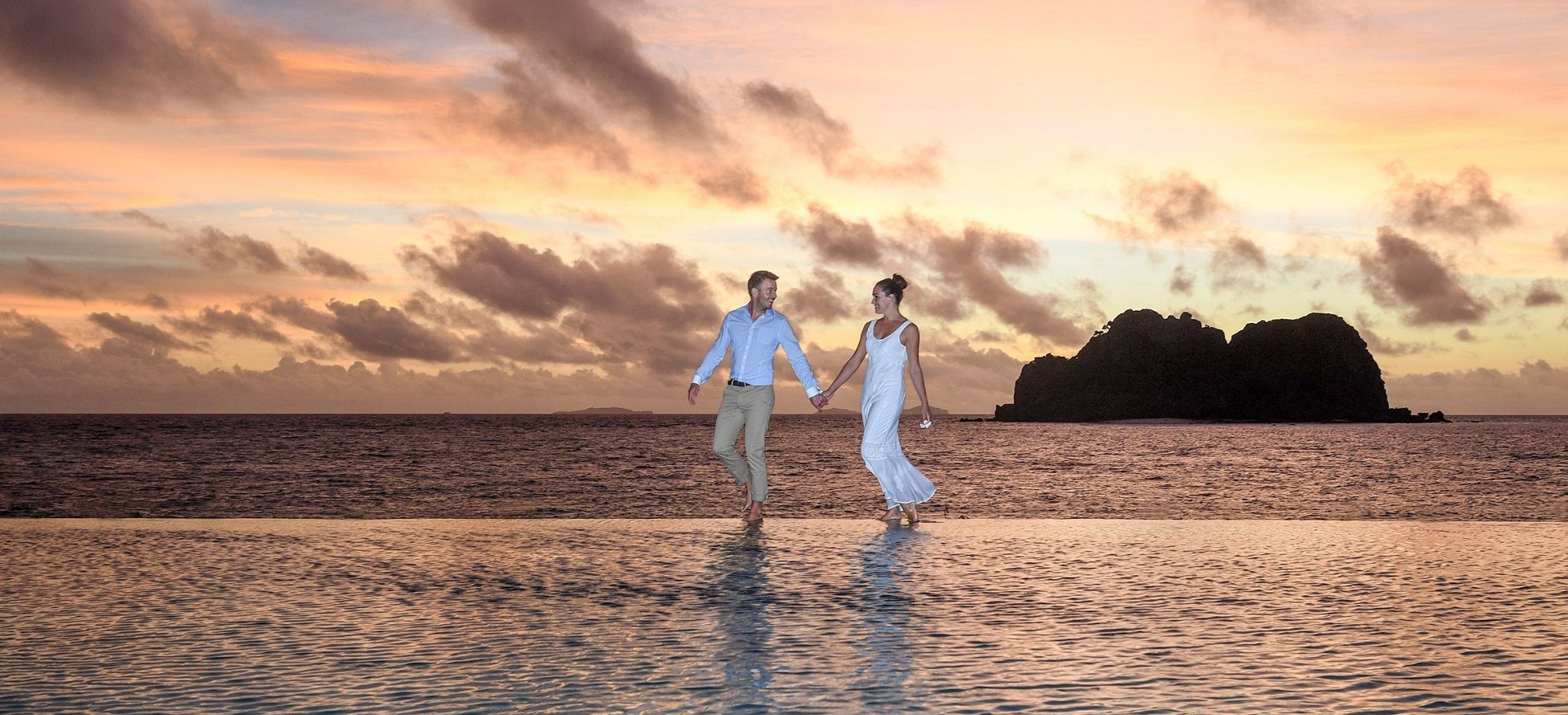 Paar läuft auf dem Resort vom Vomo Island Fiji Hotel während des Sonnenuntergangs