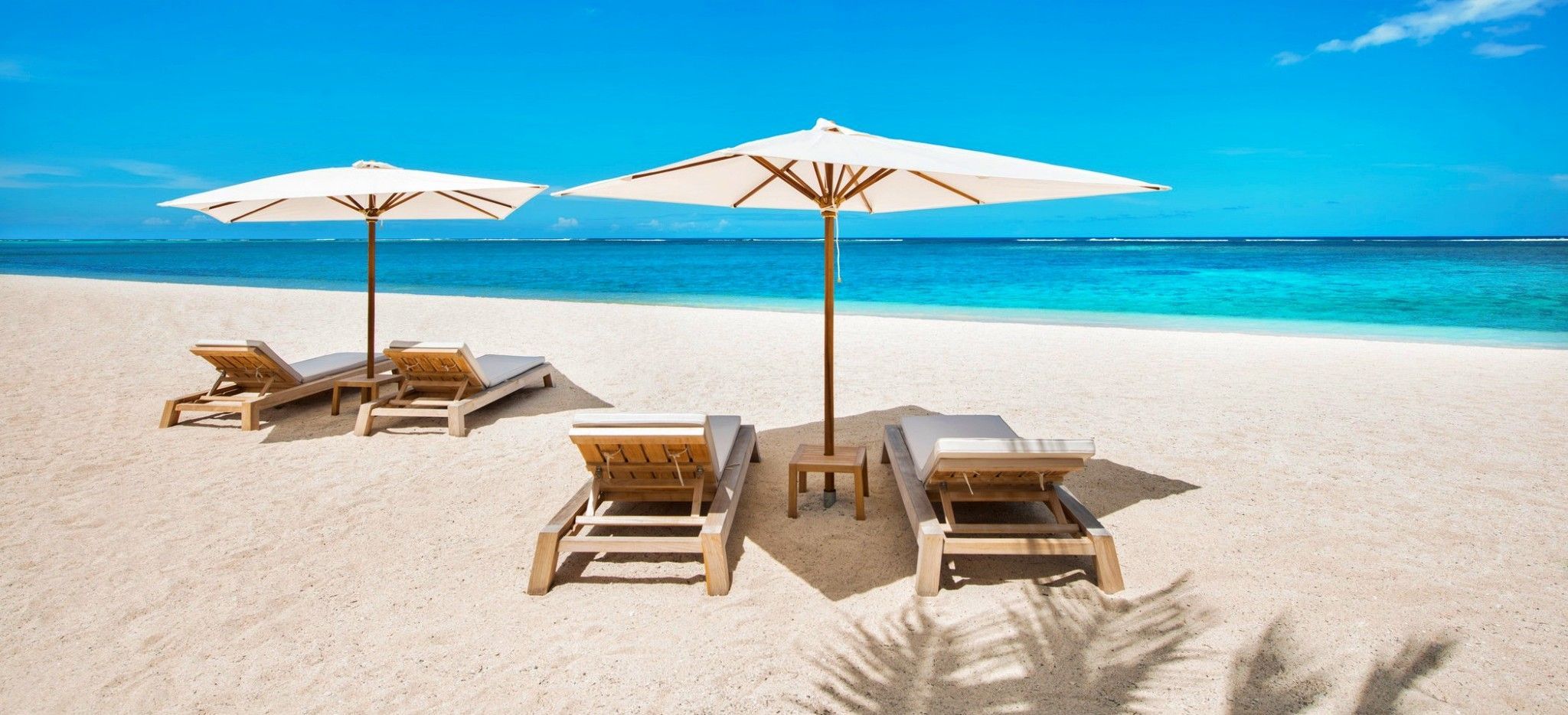 Zwei Sets Strandliegen mit Sonneschirmen am Strand auf Mauritius
