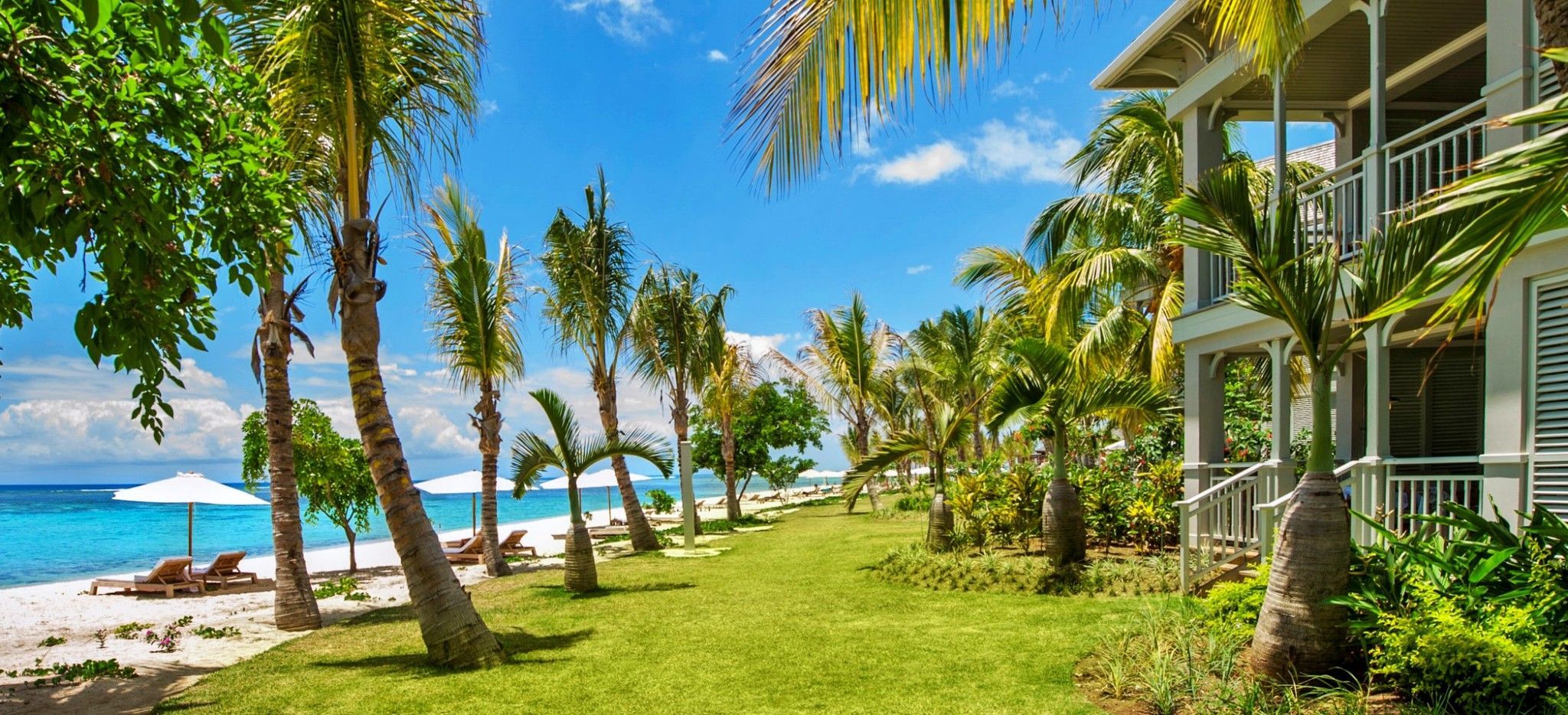 Ein Garten mit englischem Rasen zwischen Strand un dem Hotel "St. Regis Mauritius"