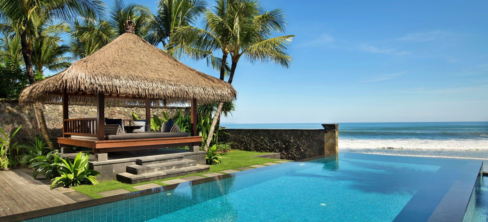 Ein pavillon neben einem Pool direkt am Strand. Im Hotel "The Legian" auf Bali