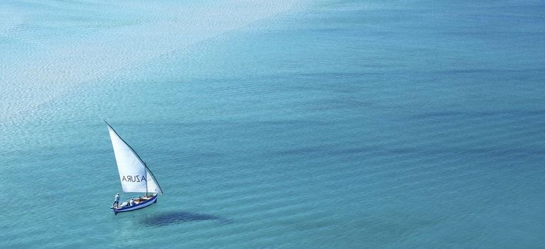 Ein traditionelles Dhow segelt über das Meer vor dem Hotel Azura Benguerra in Mosambik
