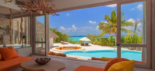 Ein ausladendes Wohnzimmer mit Blick auf einen privaten Pool und Strandzugang im Hotel Soneva Fushi auf den Malediven