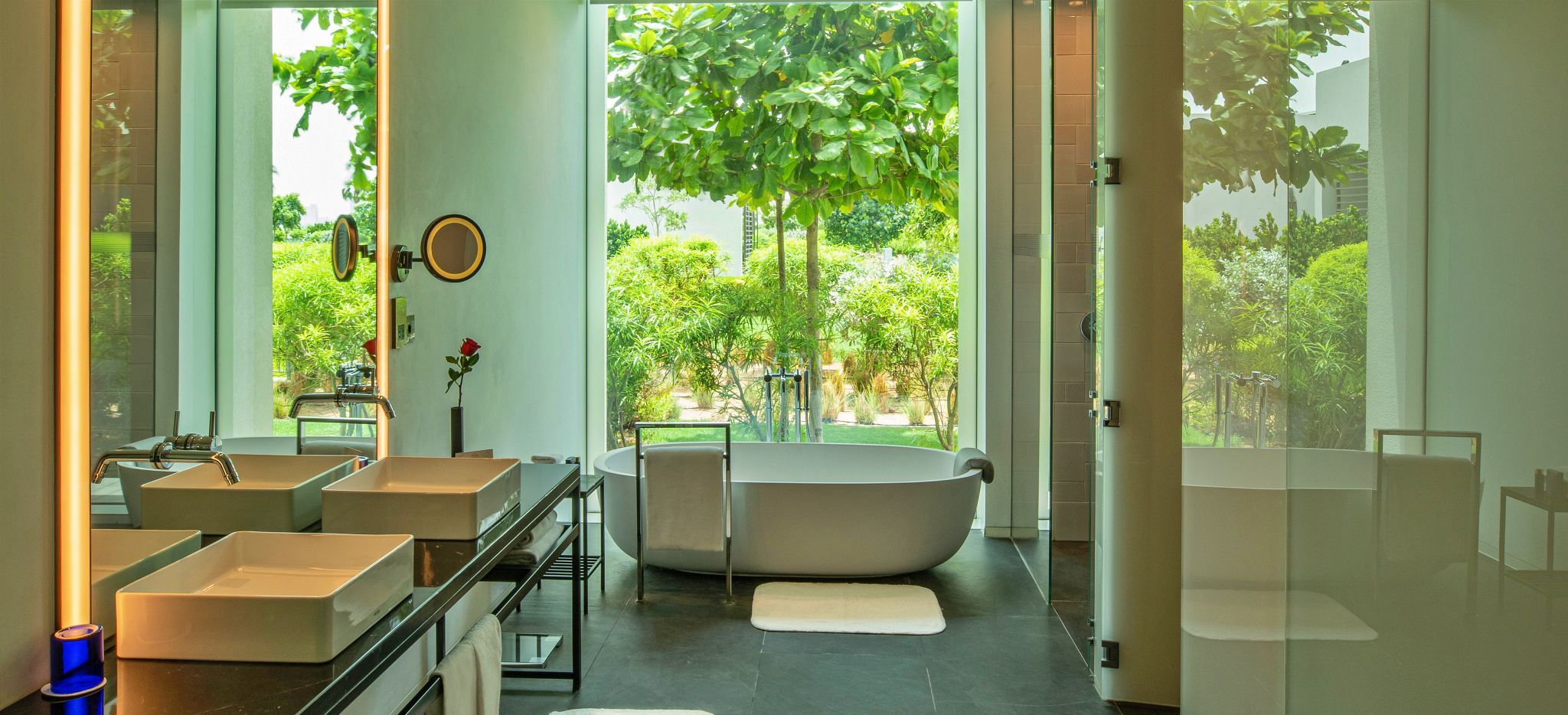 Ein Badezimmer mit Badewanne und Glasfront mit Blick auf den Garten