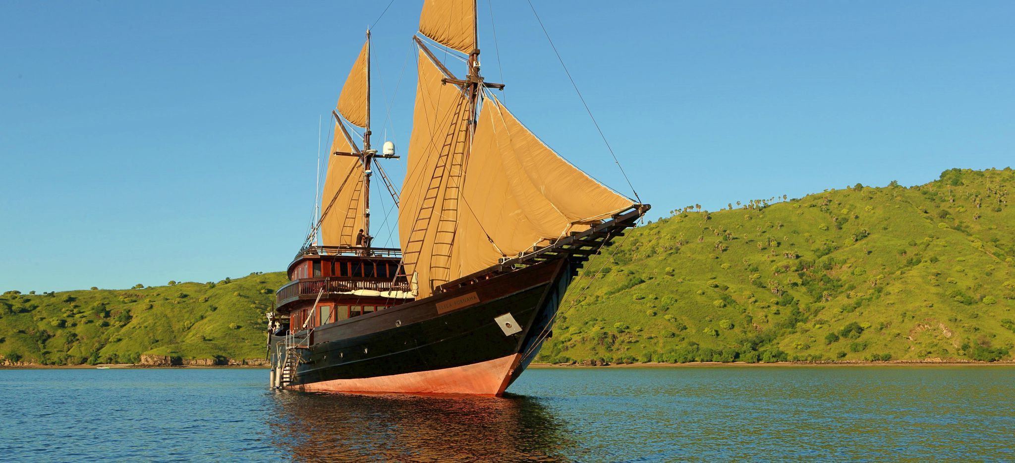 Die Yacht "Alila Purnama" auf dem Meer, mit Inseln im Hintergrund