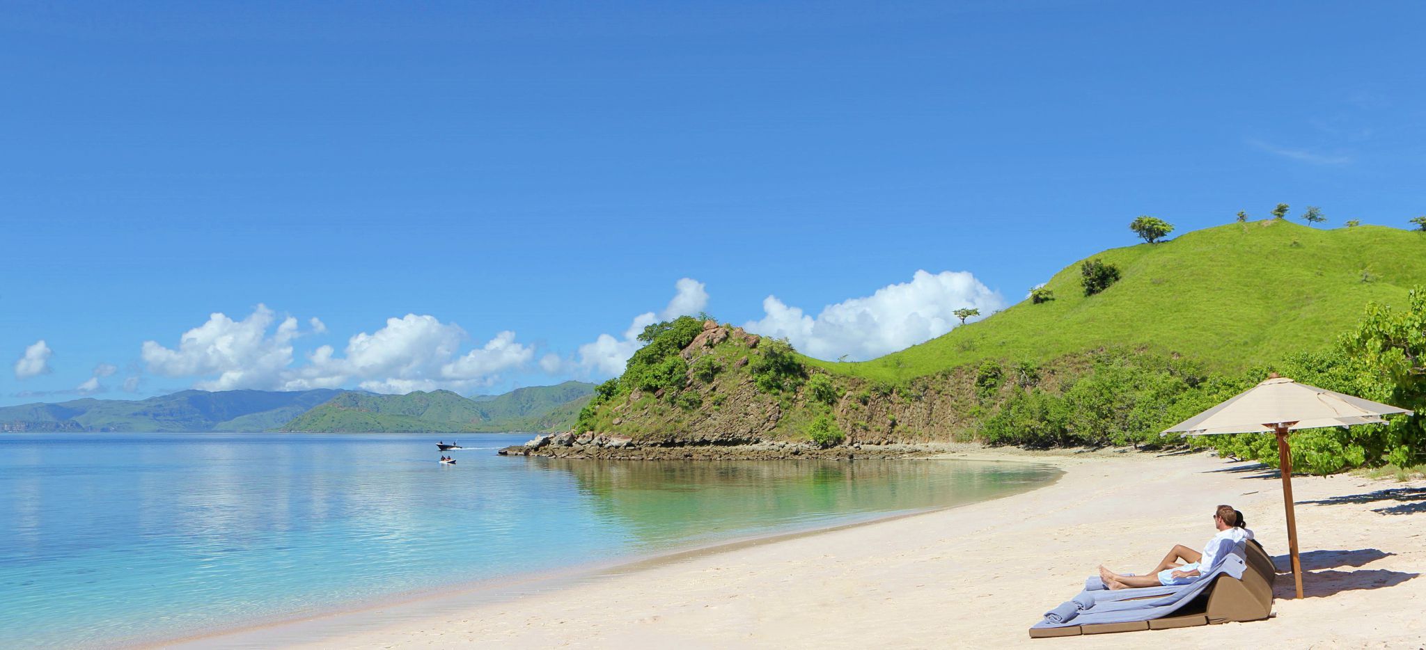 Strandliegen am Strand, Sonnenschirm, Meer und Grün, Indonesien