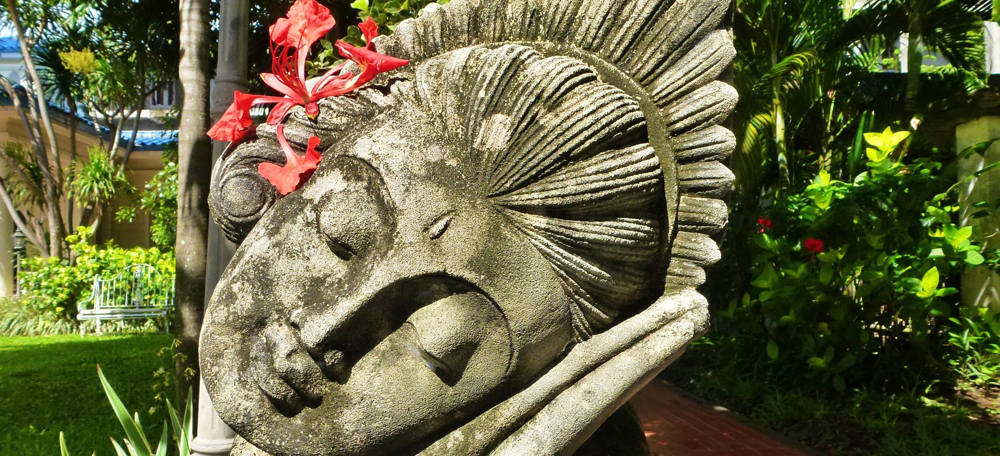 Kopf einer Statue einer Balinesischen Tänzerin, mit echter Blume hinter dem Ohr