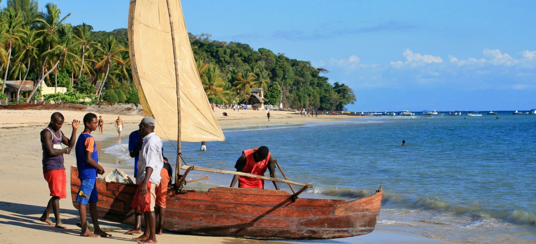 Vier Männer bereiten ein traditionelles Segelboot am Strand von Ambatoloaka auf Madagaskar vor